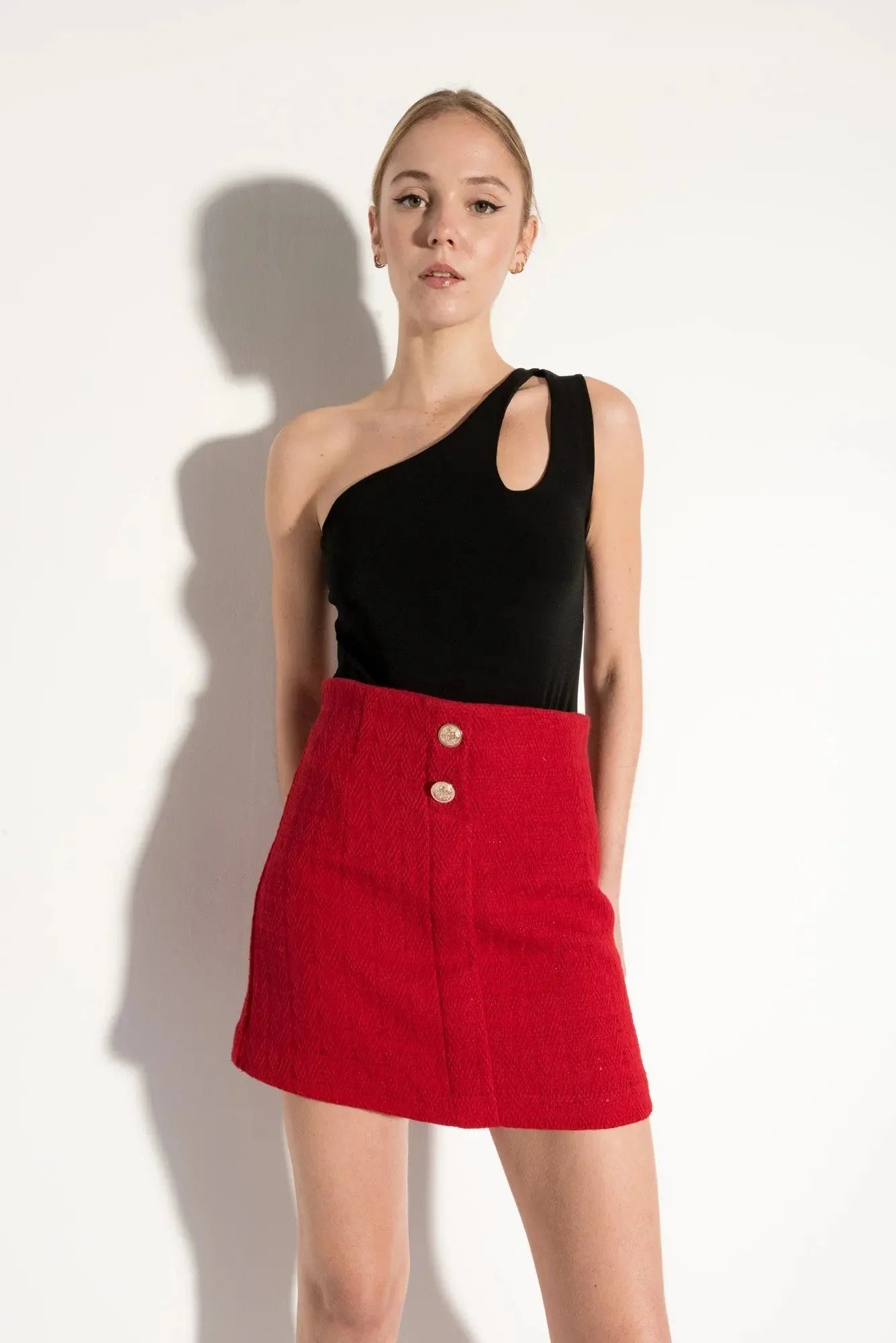 Top asymétrique noir à découpes et mini jupe rouge à boutons et poches