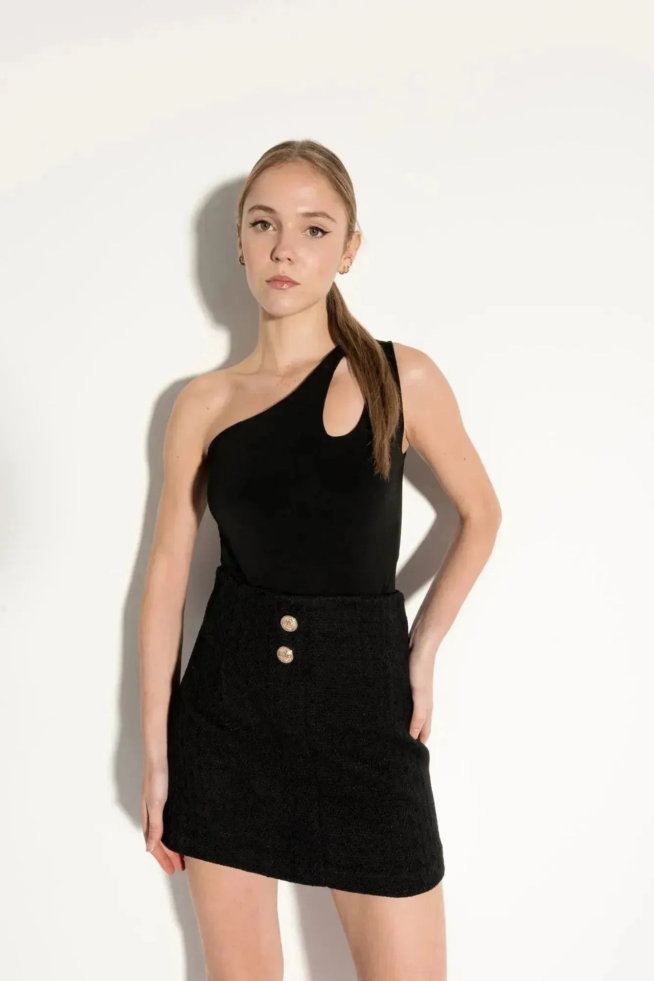 Jeune femme posant avec une jupe tweed femme, présentant sa texture et ses détails raffinés, alliant confort et élégance.