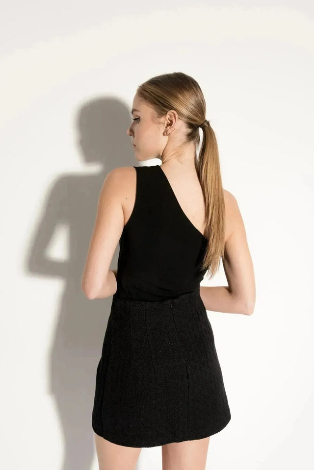 Vue arrière d'une femme portant une jupe tweed femme, mettant en avant la qualité et le design soigné du vêtement.