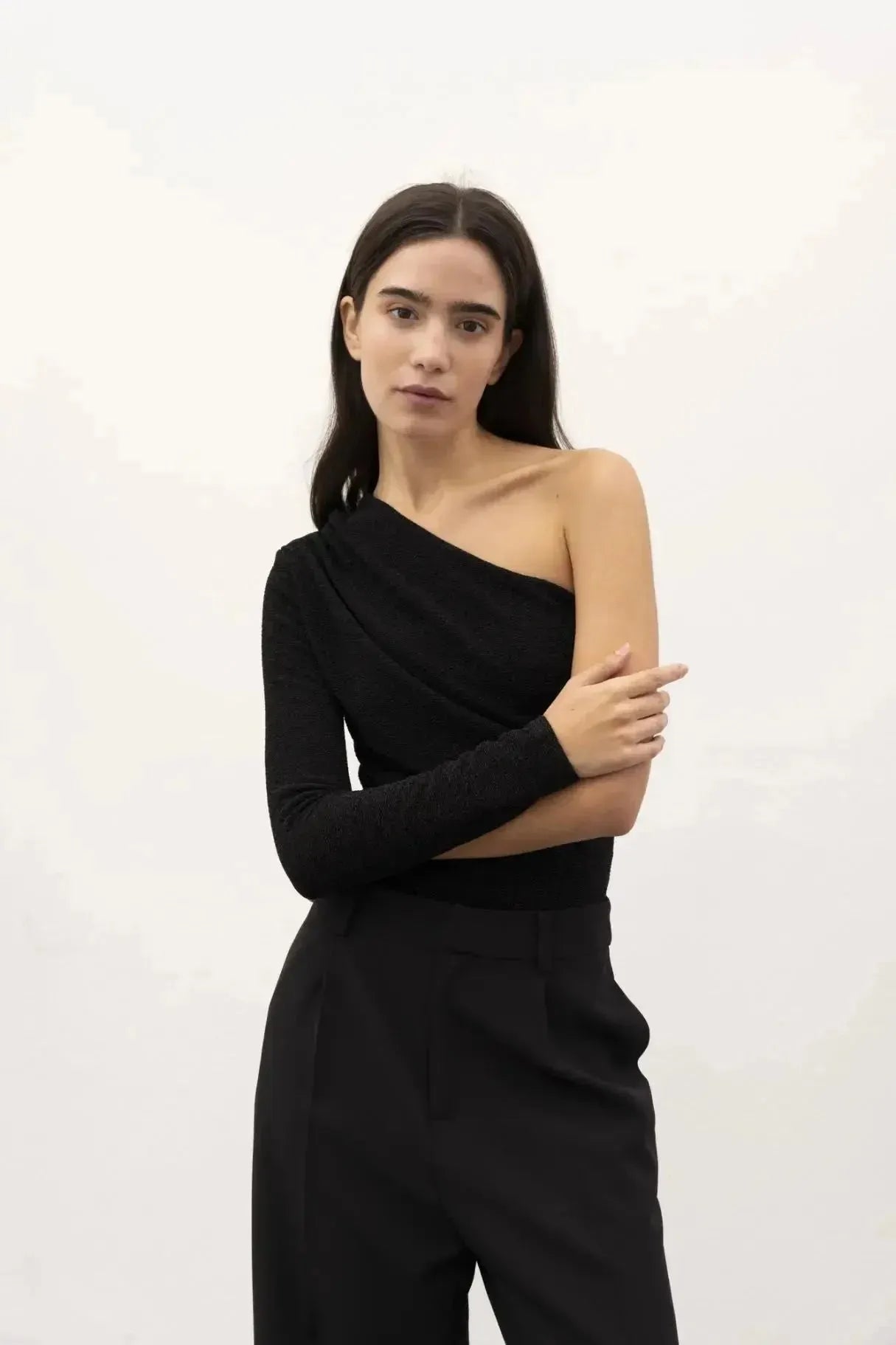 Une autre vue du modèle en body asymétrique, avec un bras croisé contre la poitrine, mettant en avant le tissu texturé.