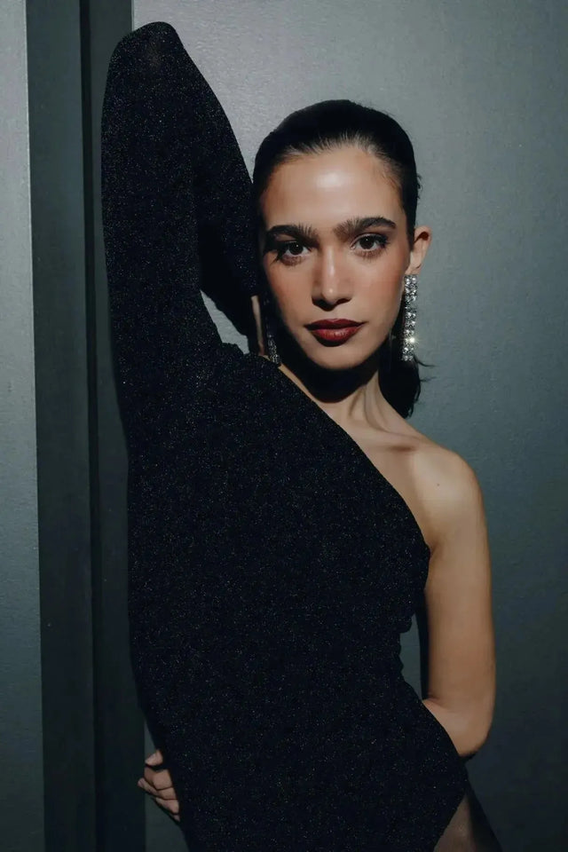 Close-up sur un modèle en body asymétrique, mettant en valeur le bras levé et des boucles d'oreilles scintillantes, illustrant le style moderne du body asymétrique.