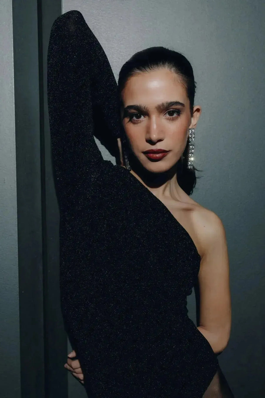 Close-up sur un modèle en body asymétrique, mettant en valeur le bras levé et des boucles d'oreilles scintillantes, illustrant le style moderne du body asymétrique.