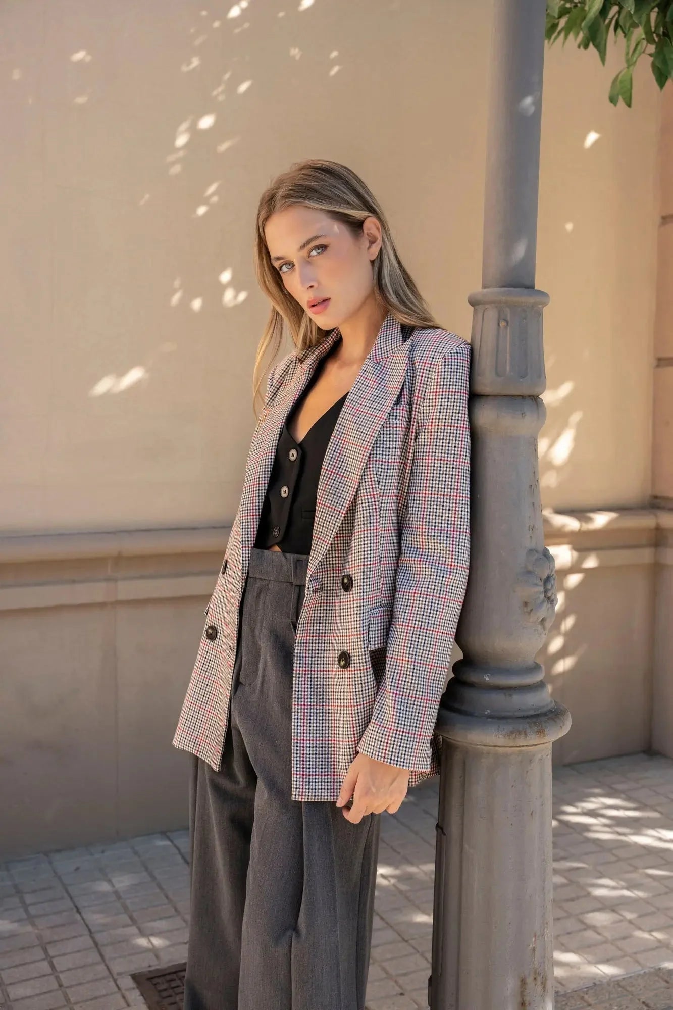 Modèle avec le blazer femme double boutonnage à carreaux de Sapiato, stylé avec un pantalon gris élégant.