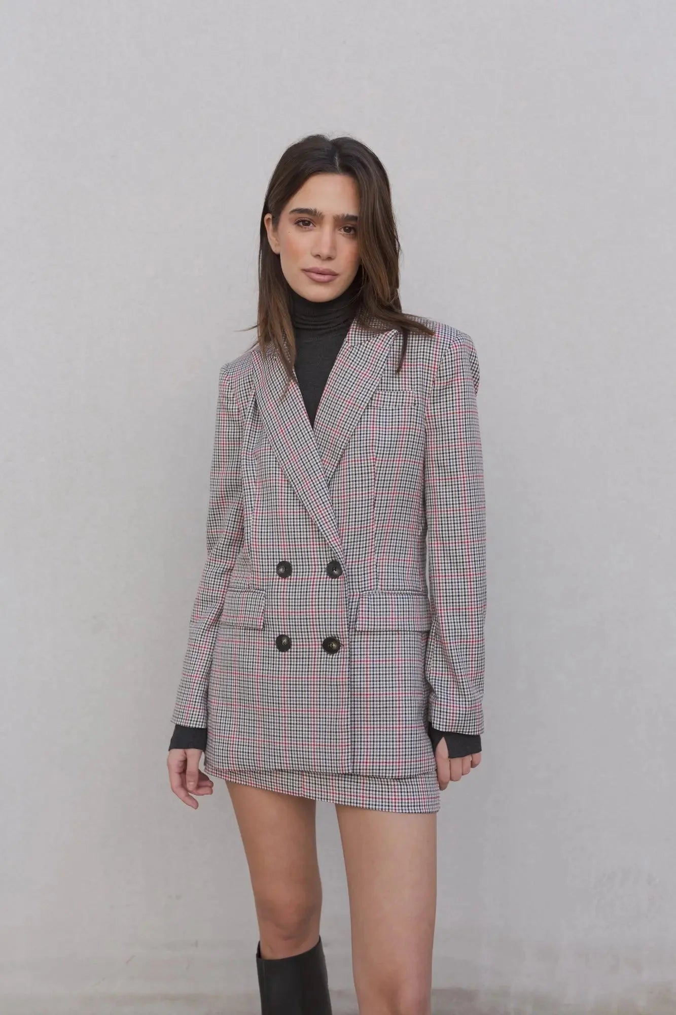 Premier plan d'un modèle en blazer femme double boutonnage à carreaux, montrant les détails des boutons et de la coupe.