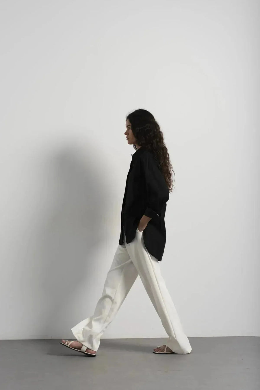 Femme portant un ensemble blazer et pantalon plissé blanc avec sandales élégantes
