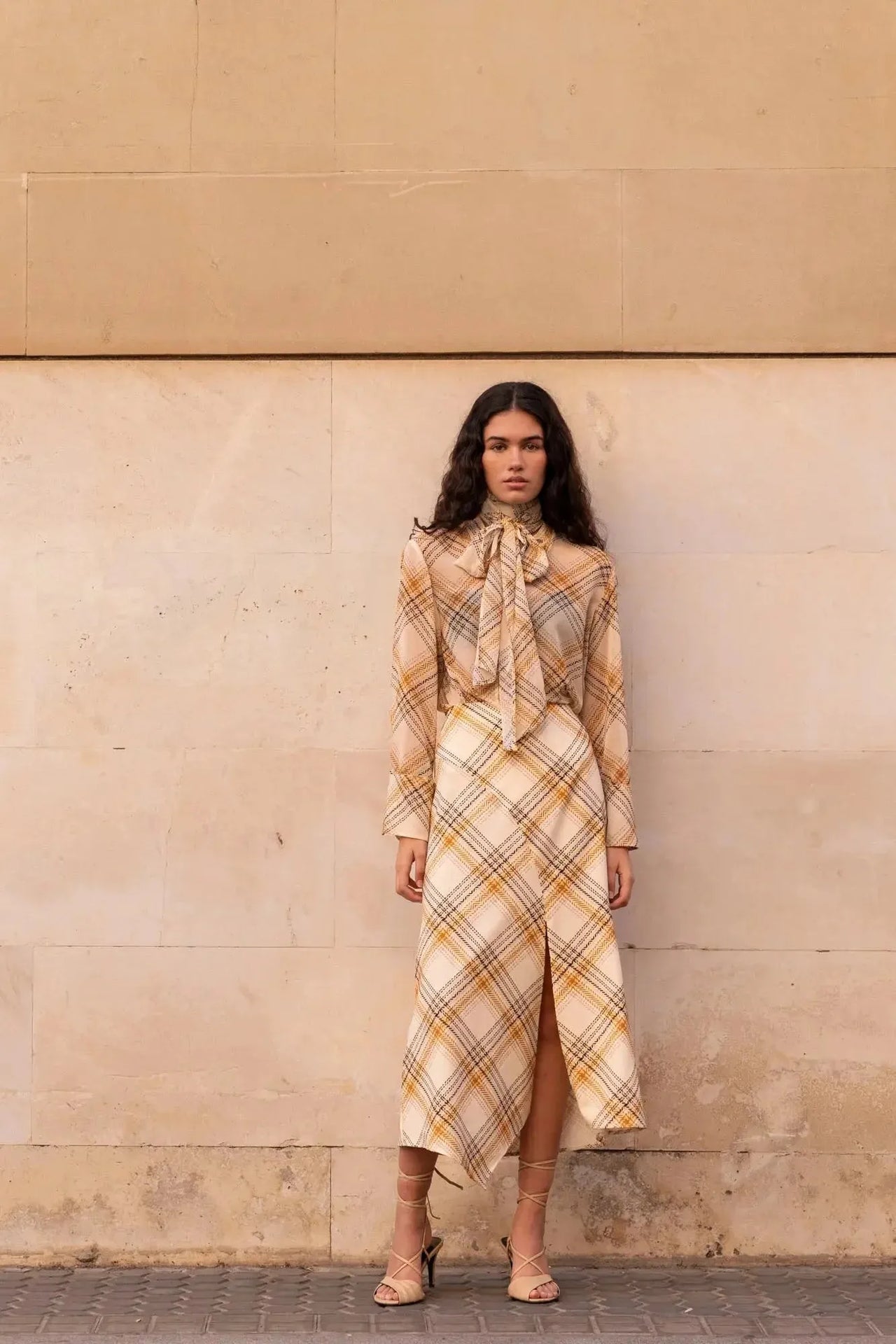 Femme affichant un style élégant avec un chemisier cravate femme à carreaux, parfait pour un événement chic.