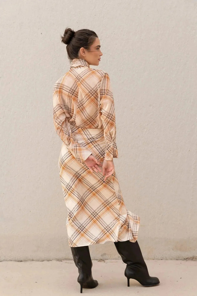 Femme de dos portant un chemisier cravate femme à carreaux, mettant en avant sa coupe ample et élégante.