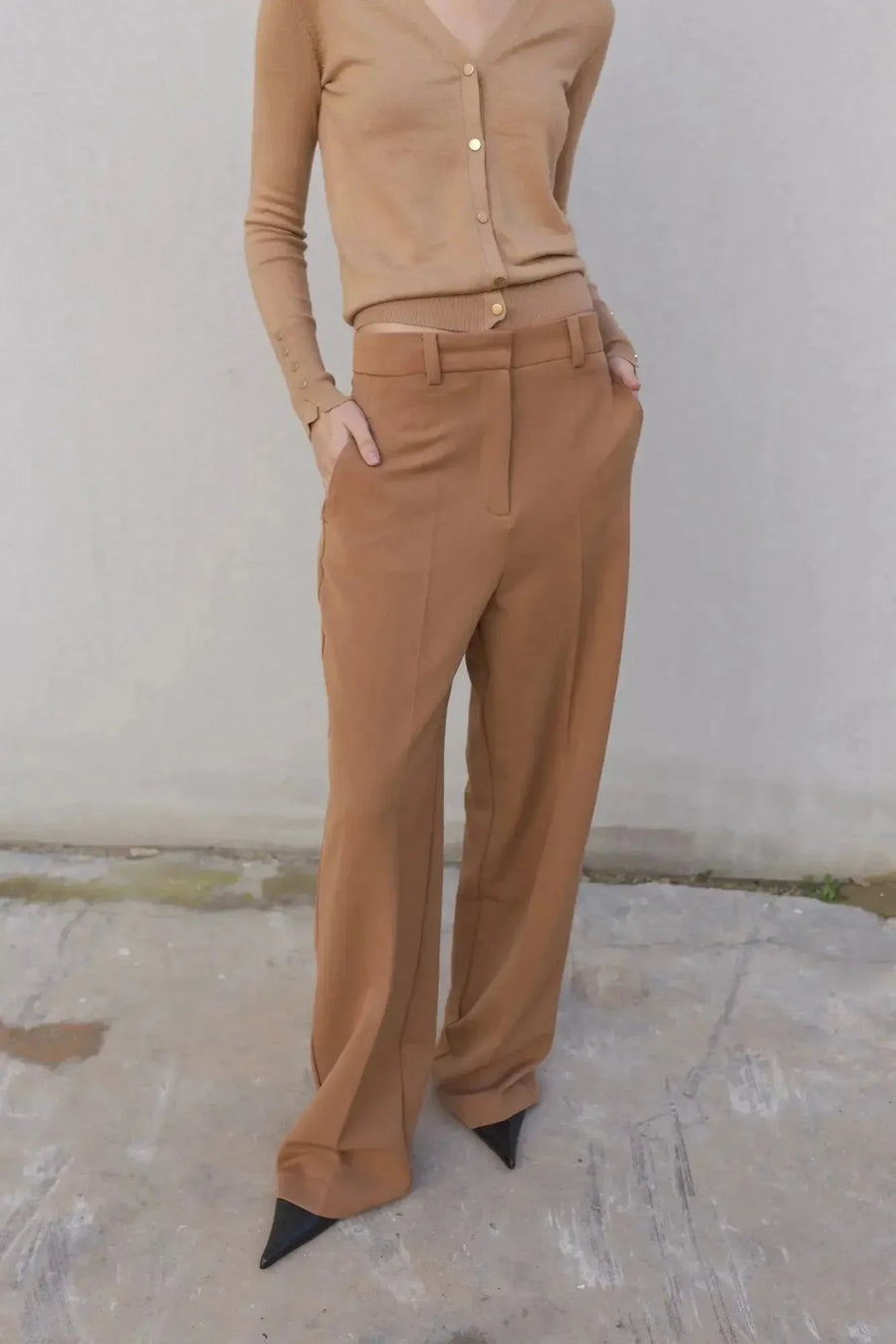 Femme arborant un style chic dans un gilet tricot femme beige et un pantalon marron, capturant l'essence de l'élégance décontractée.