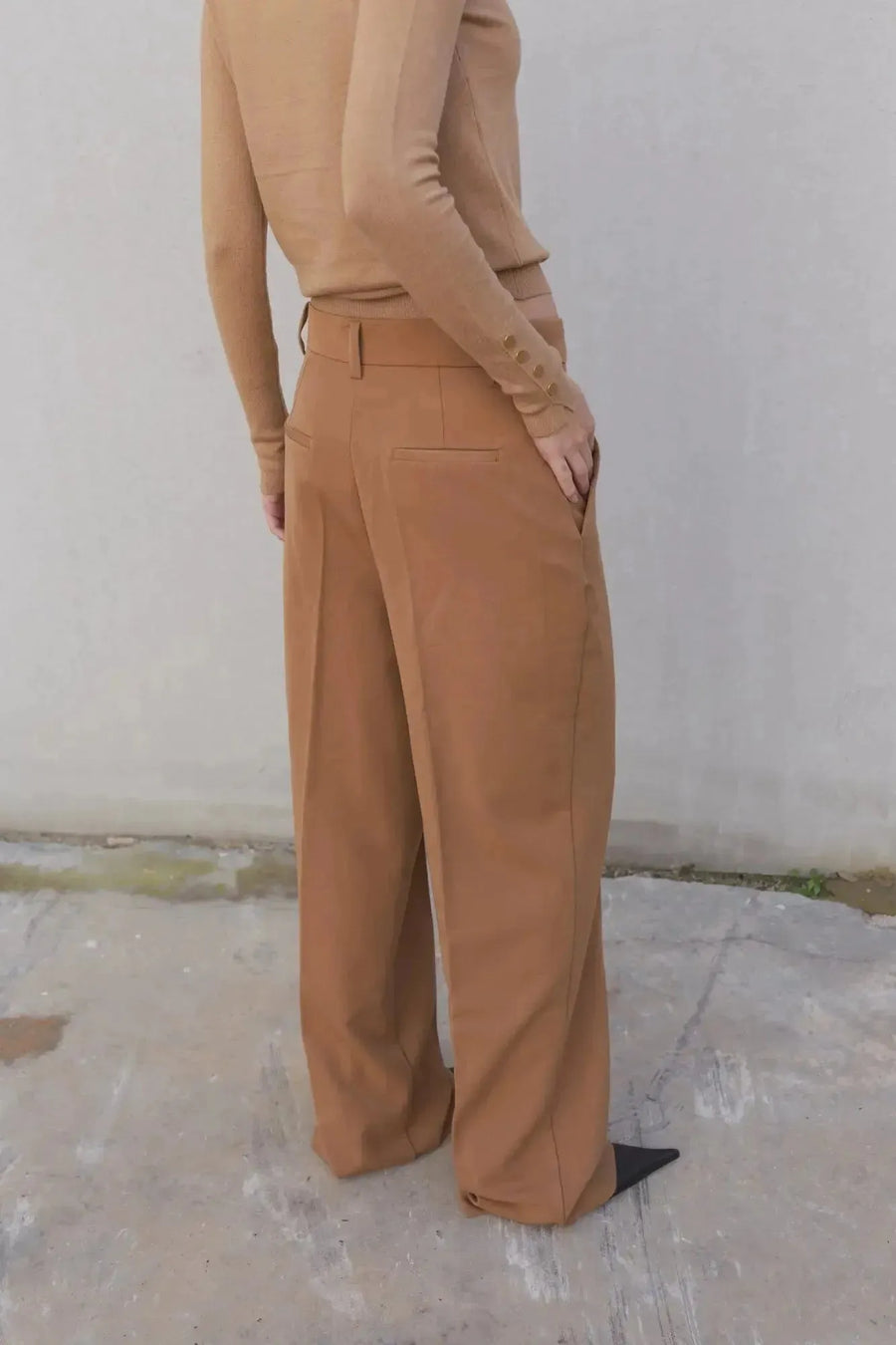 Vue arrière d'une femme dans un gilet tricot femme beige avec boutons, combiné avec un pantalon marron, mettant en avant le confort.