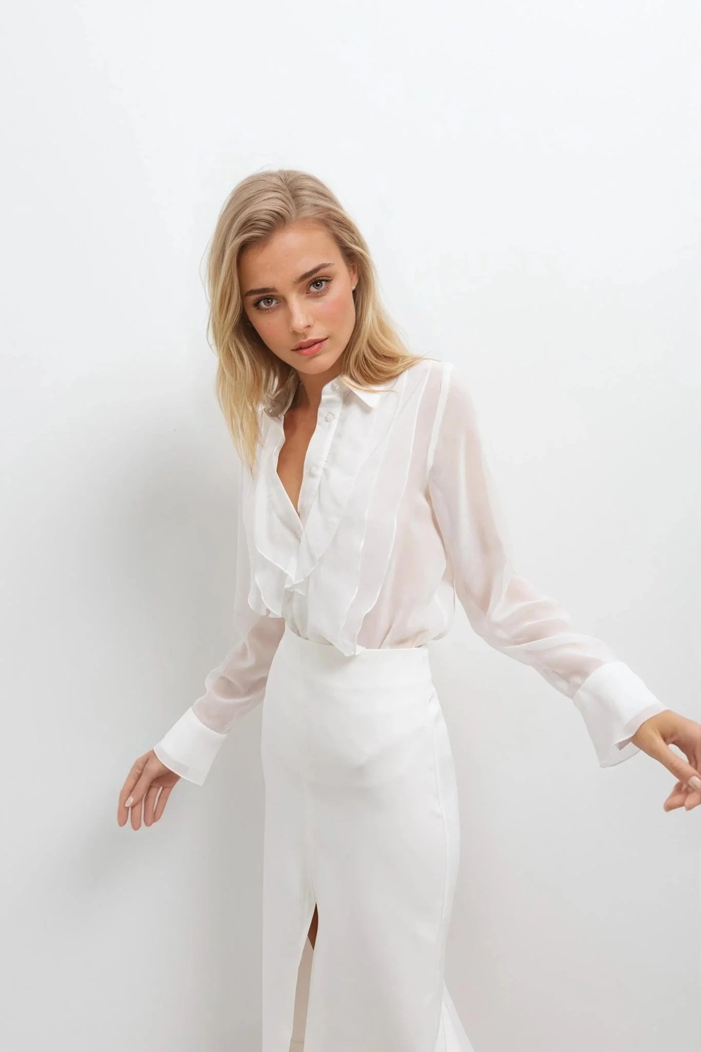 Femme blonde portant une chemise à volants blanche et une jupe fendue longue