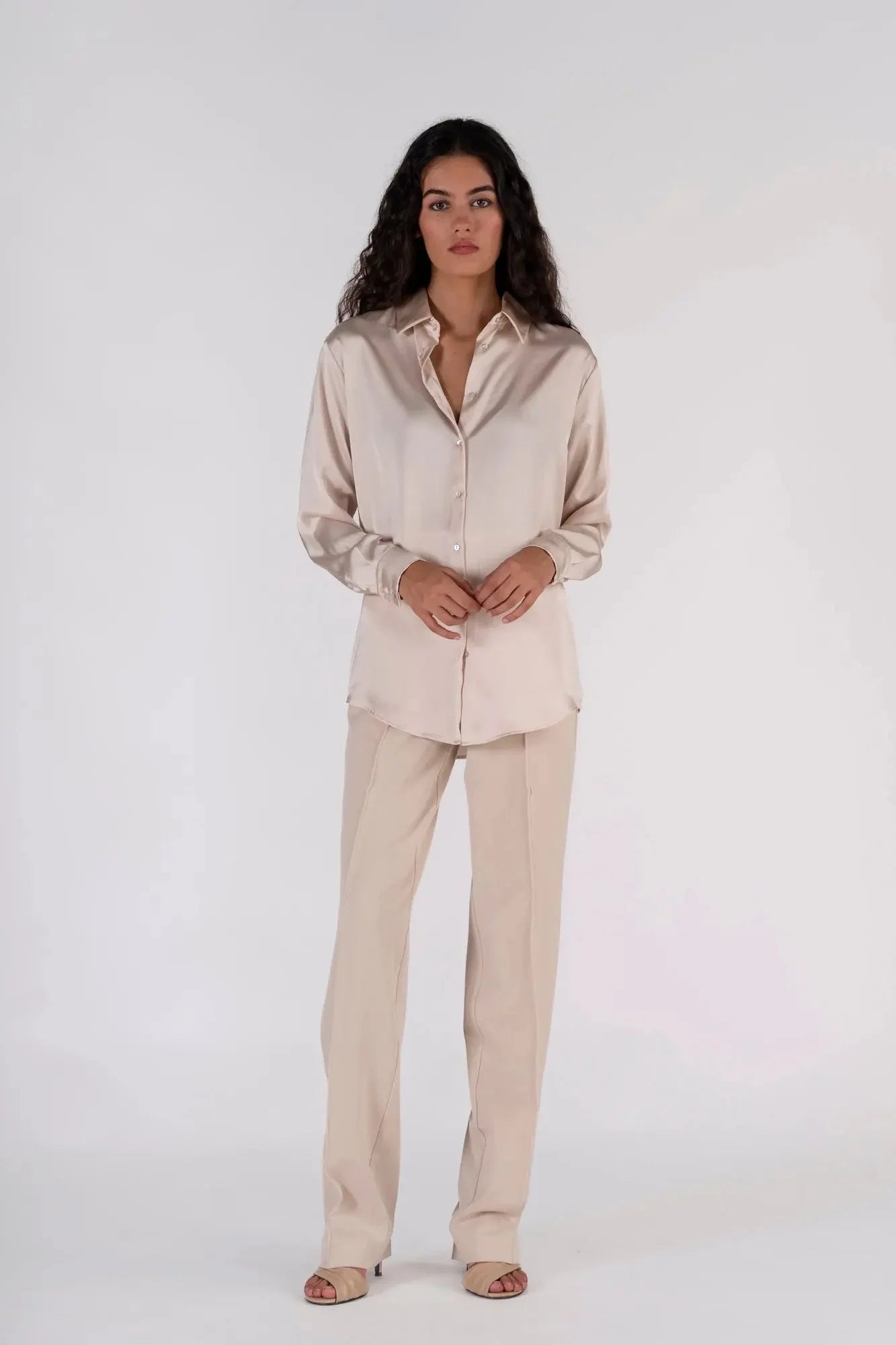 Femme avec une chemise en satin femme dans un style élégant, associée à un pantalon beige, parfaite pour le travail.