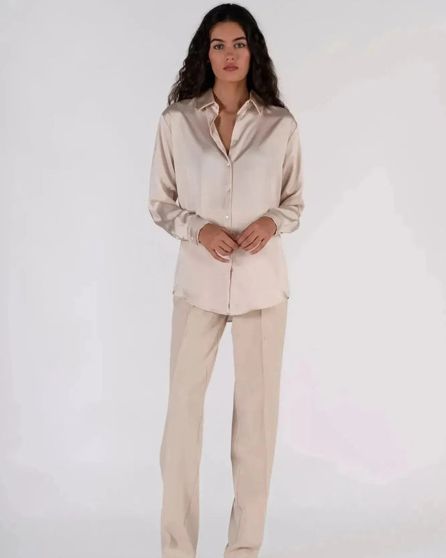 Femme avec une chemise en satin femme dans un style élégant, associée à un pantalon beige, parfaite pour le travail.