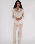 Femme avec une chemise en satin femme dans un style élégant, associée à un pantalon beige, parfaite pour le travail.