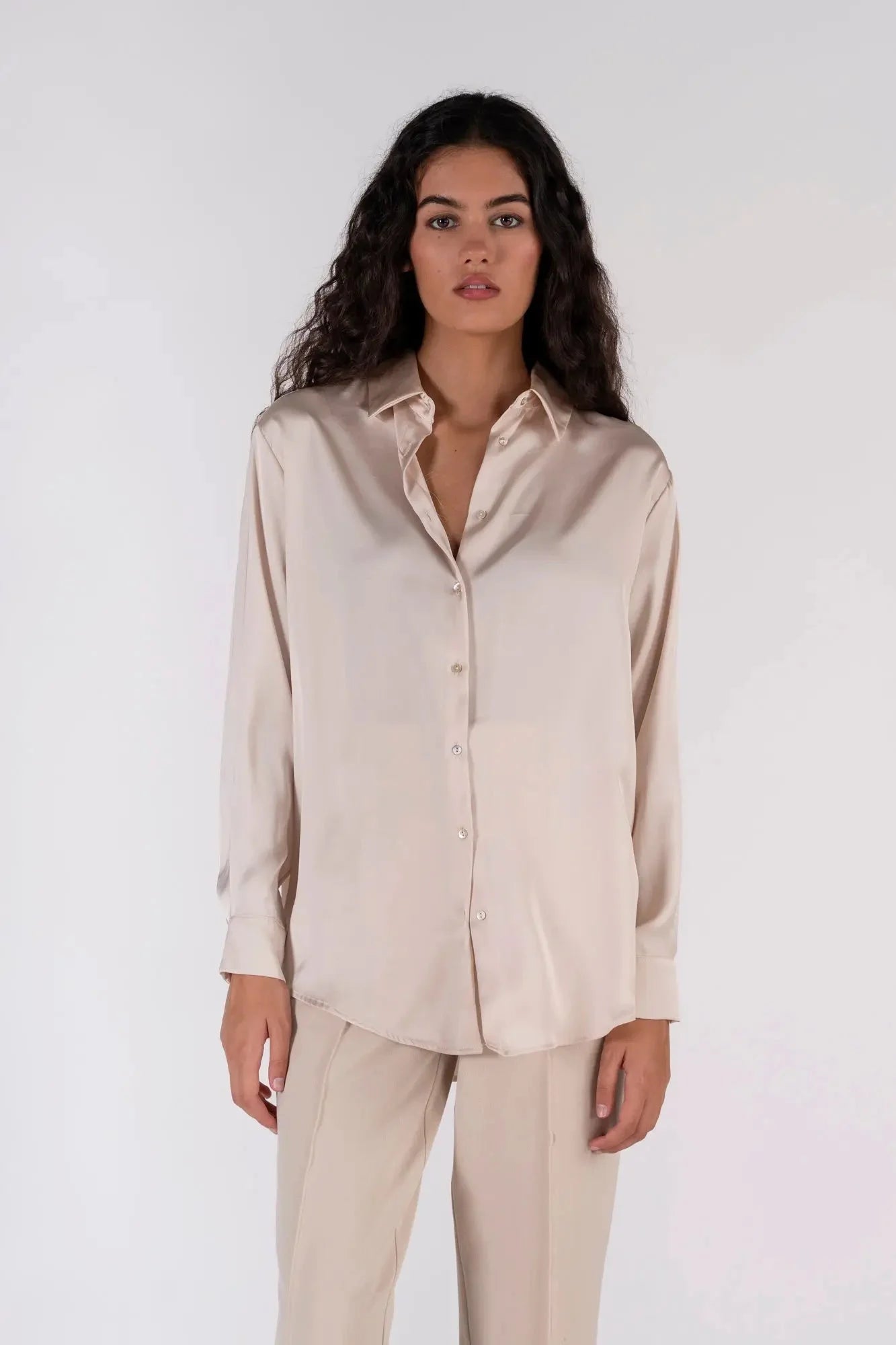 Femme élégante en chemise en satin femme, posant pour mettre en valeur son look professionnel.