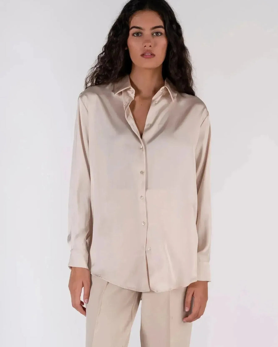 Femme élégante en chemise en satin femme, posant pour mettre en valeur son look professionnel.
