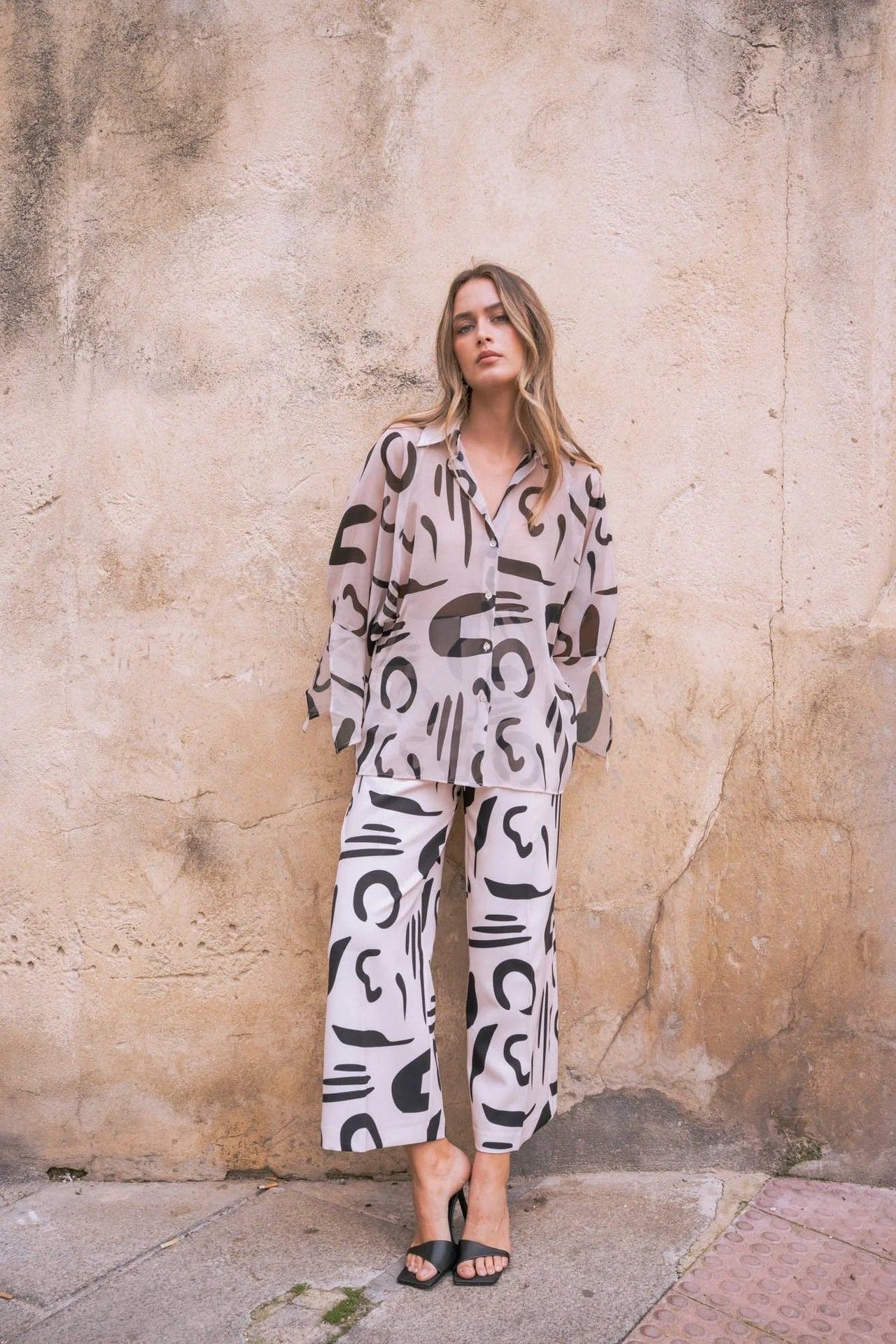 Modèle portant un ensemble chemise et pantalon imprimé motif abstrait, mettant en avant un pantalon fluide femme et un style artistique.