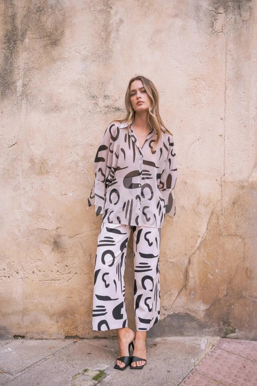 Modèle portant un ensemble chemise et pantalon imprimé motif abstrait, mettant en avant un pantalon fluide femme et un style artistique.