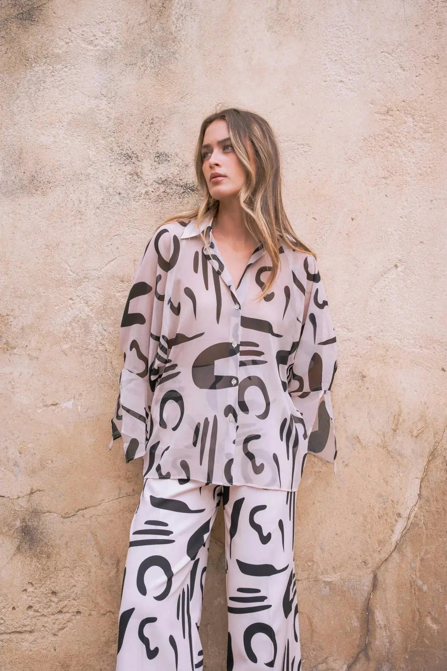 Détail d'un ensemble chemise et pantalon imprimé motif abstrait, soulignant le pantalon fluide femme pour un look moderne et audacieux.
