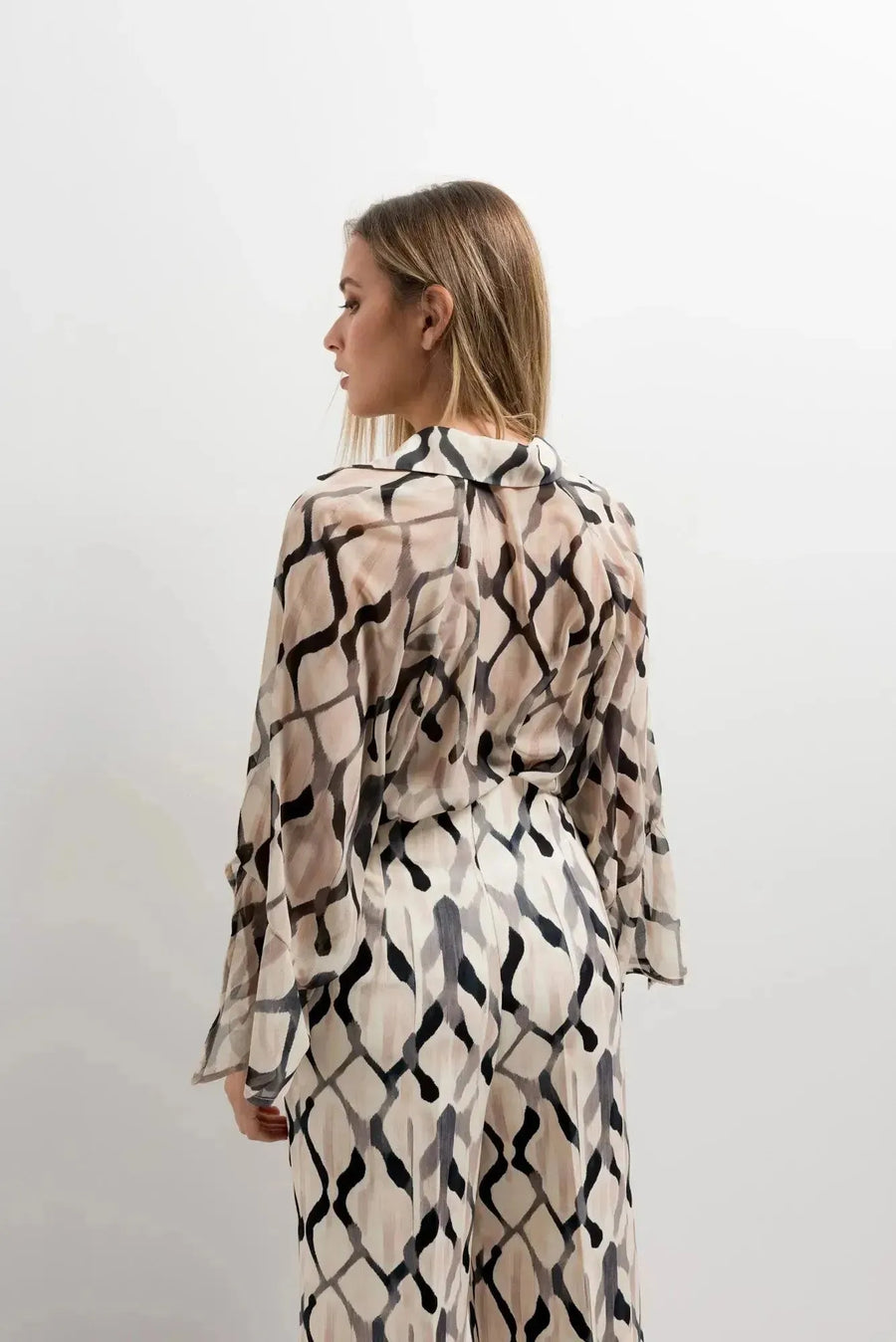 Femme montrant l'arrière de son ensemble chemise et pantalon imprimée culotte, soulignant le look tendance du pantalon culotte femme.