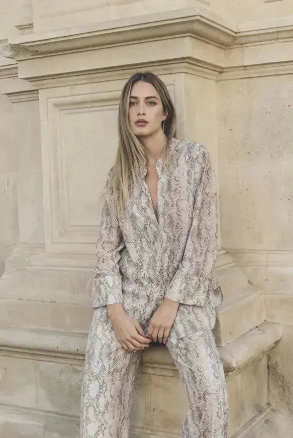 Femme posant avec confiance dans une chemise imprimée animal femme, assise devant un bâtiment élégant.