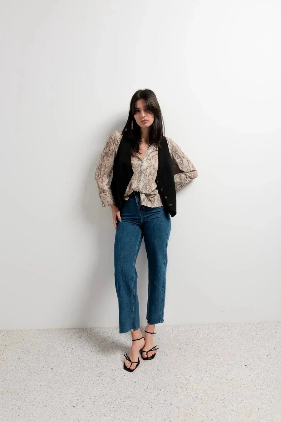 Femme stylée dans une chemise imprimée animal femme, portant un gilet noir et un jean pour un look décontracté.