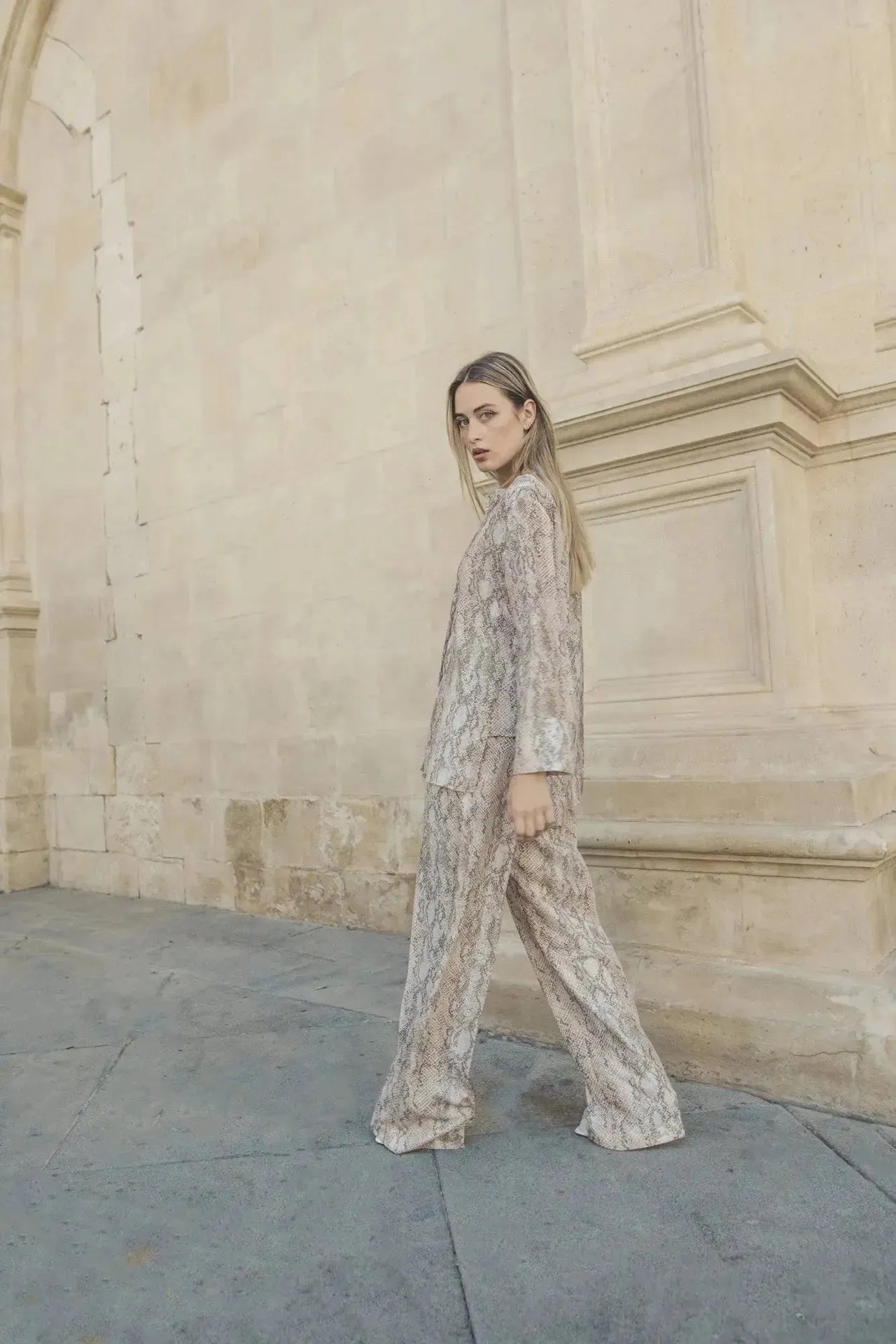 Femme défilant dans une chemise imprimée animal femme, montrant un look sophistiqué devant une architecture classique.