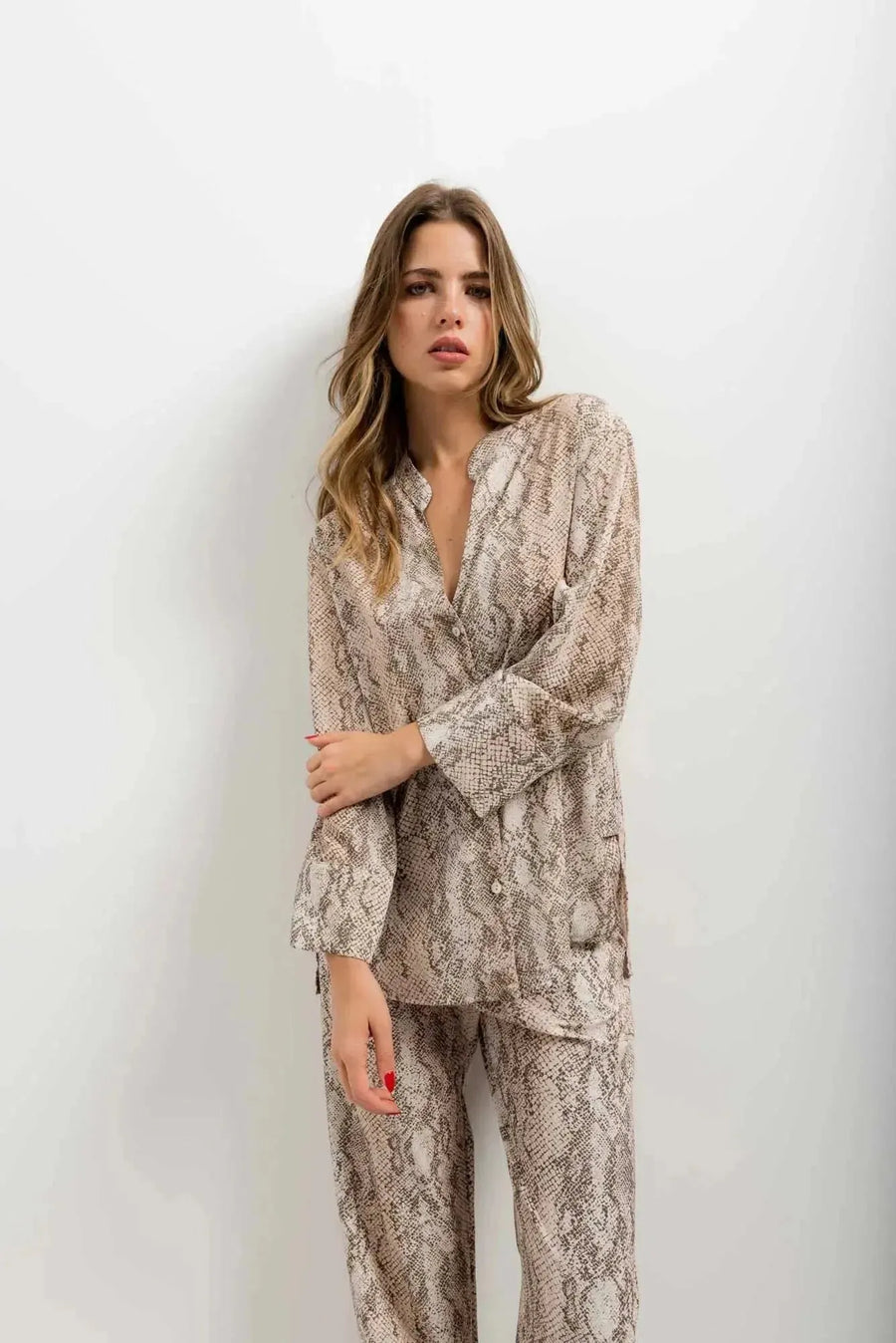 Modèle portant une chemise imprimée animal femme dans un style élégant, se tenant contre un mur blanc.