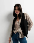 Modèle avec une chemise imprimée animal femme et gilet noir, affichant une allure moderne et tendance.