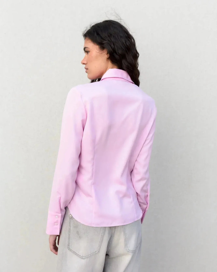 Détail de la chemise femme cintrée rose pastel sur une femme, montrant la coupe élégante et ajustée, vêtue d’un jean.