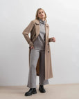 Femme élégante dans un gilet sans manche femme, portant un ensemble col roulé et pantalon large gris avec un trench-coat.