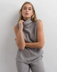Femme posant avec un gilet sans manche femme sur un ensemble col roulé et pantalon large gris, montrant une allure chic.