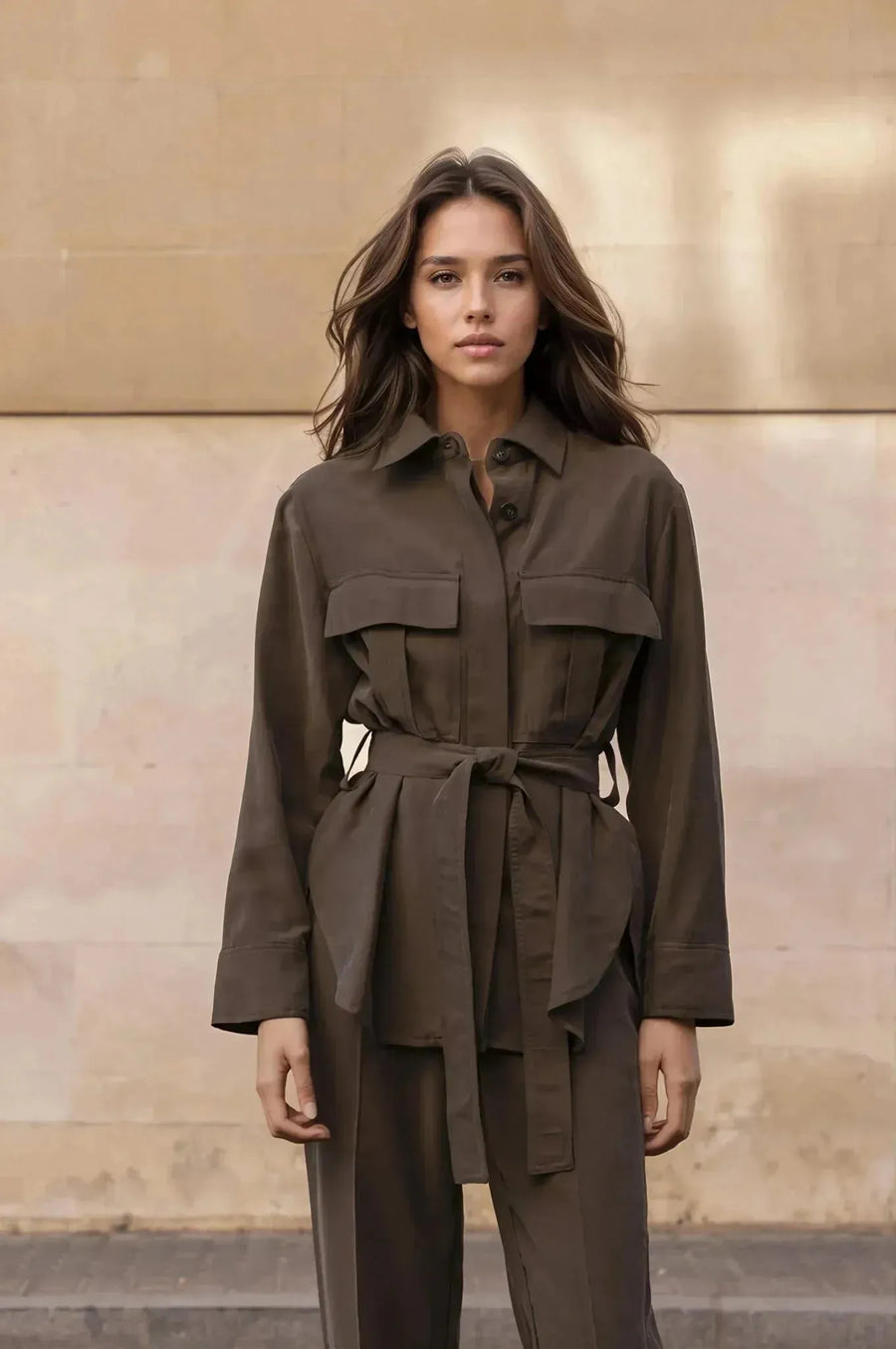 Ensemble coordonné chemise et pantalon kaki femme, portrait devant un mur en pierre, style moderne.