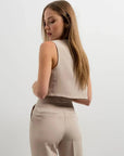 Femme montrant le dos de son gilet de costume femme court beige élégant et confortable, mettant en valeur sa silhouette. Une pièce à porter en toute occasion.