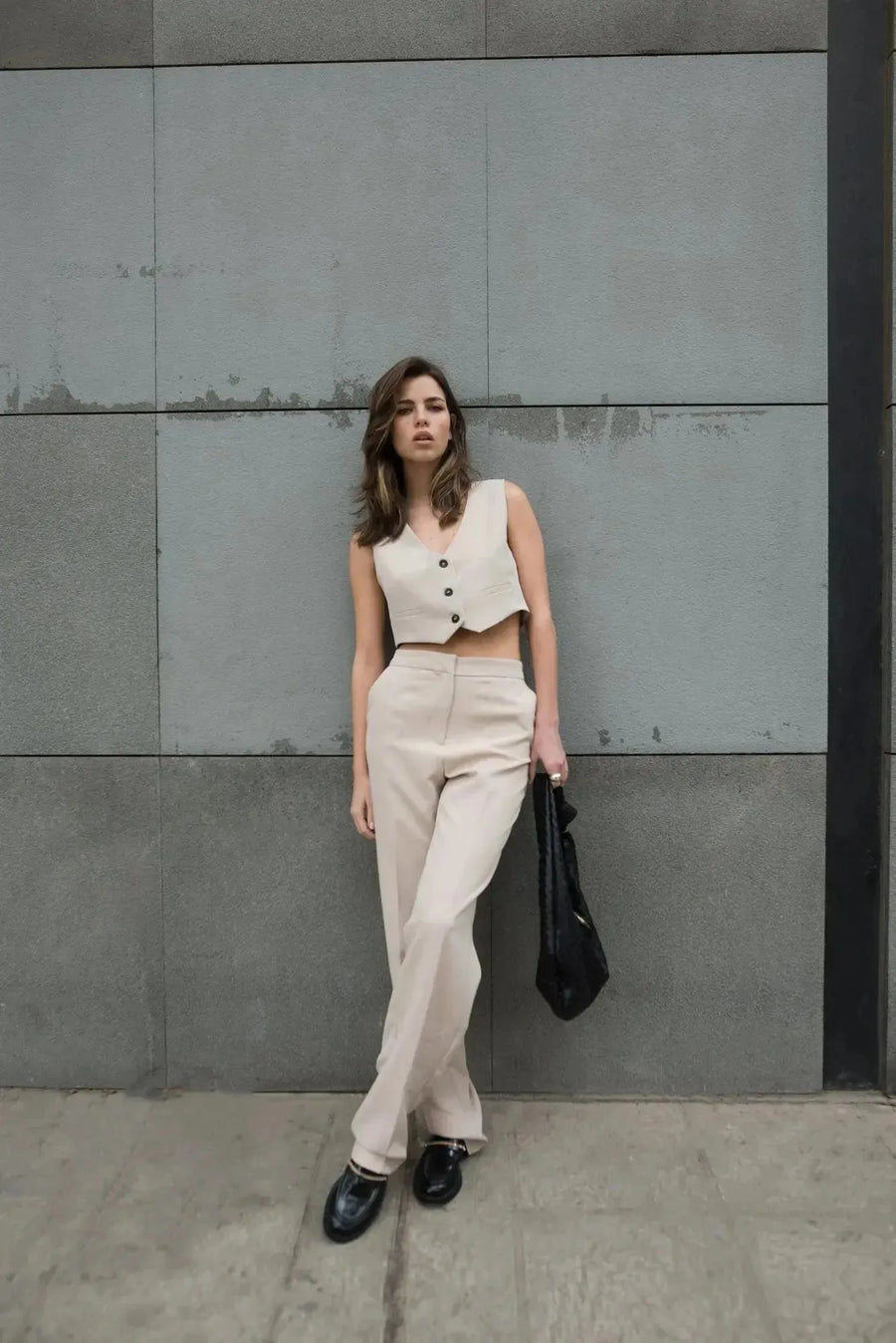 Femme posant avec style dans un gilet de costume femme court beige élégant et confortable, mettant en avant une tenue chic. Parfait pour diverses occasions.