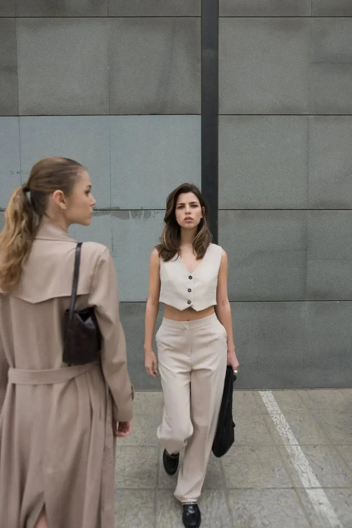 Femme portant un gilet de costume femme court beige élégant et confortable, marchant avec assurance dans un cadre urbain. Idéal pour toutes occasions.