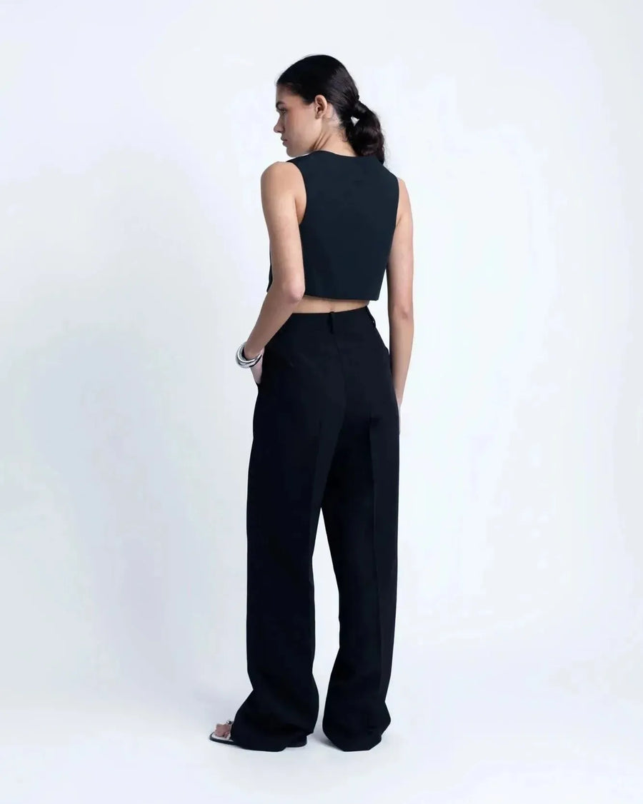Modèle vue de profil portant un gilet costume femme court avec un pantalon noir, une tenue moderne et sophistiquée.