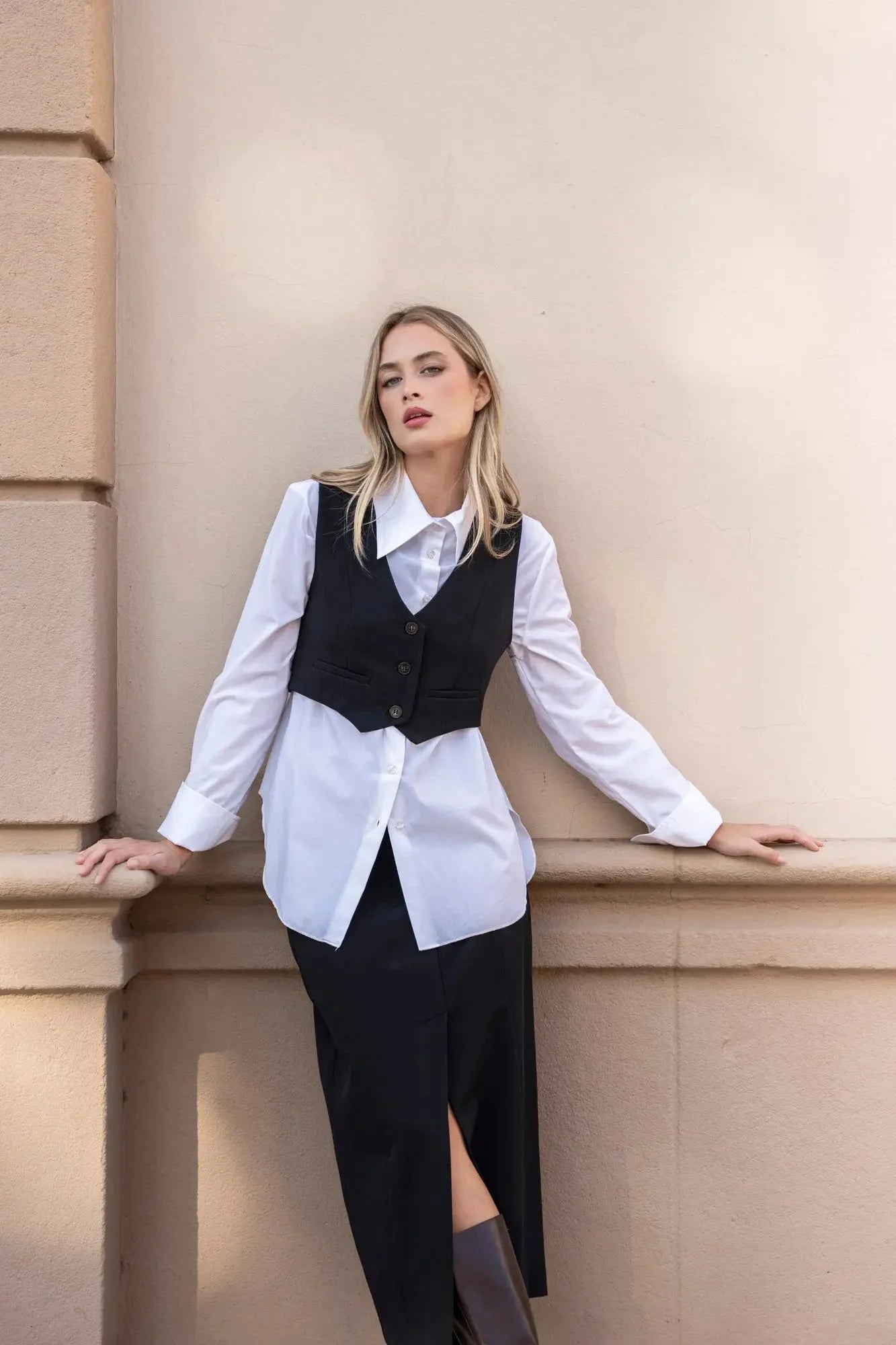 Femme portant un gilet court noir, touche tendance, sur chemise blanche et jupe noire midi