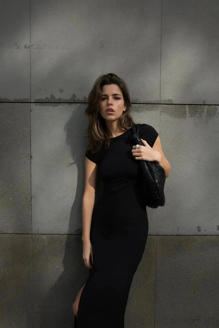 Détails d'une jeune femme avec une jupe noire fendue, accentuant le glamour et la modernité de la mode actuelle.