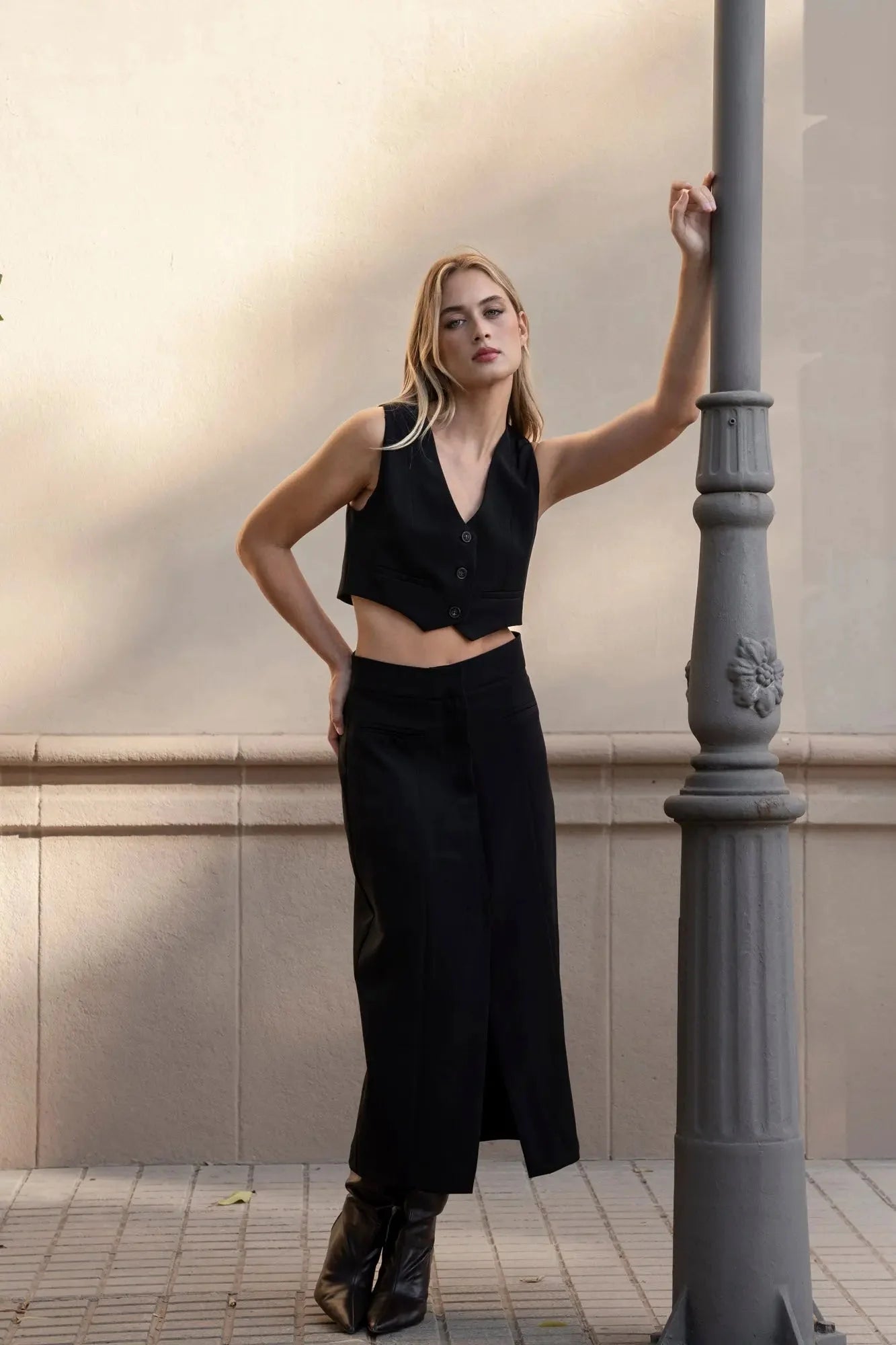 Femme portant une jupe noire fendue, élégante et tendance, associée à un top court, pour un look chic et stylé.