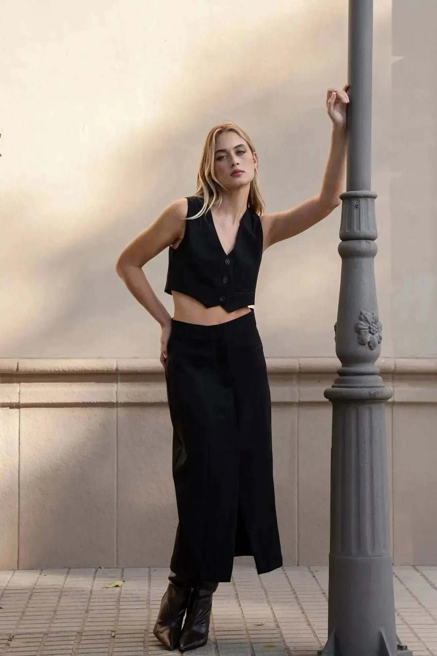 Femme portant une jupe noire fendue, élégante et tendance, associée à un top court, pour un look chic et stylé.