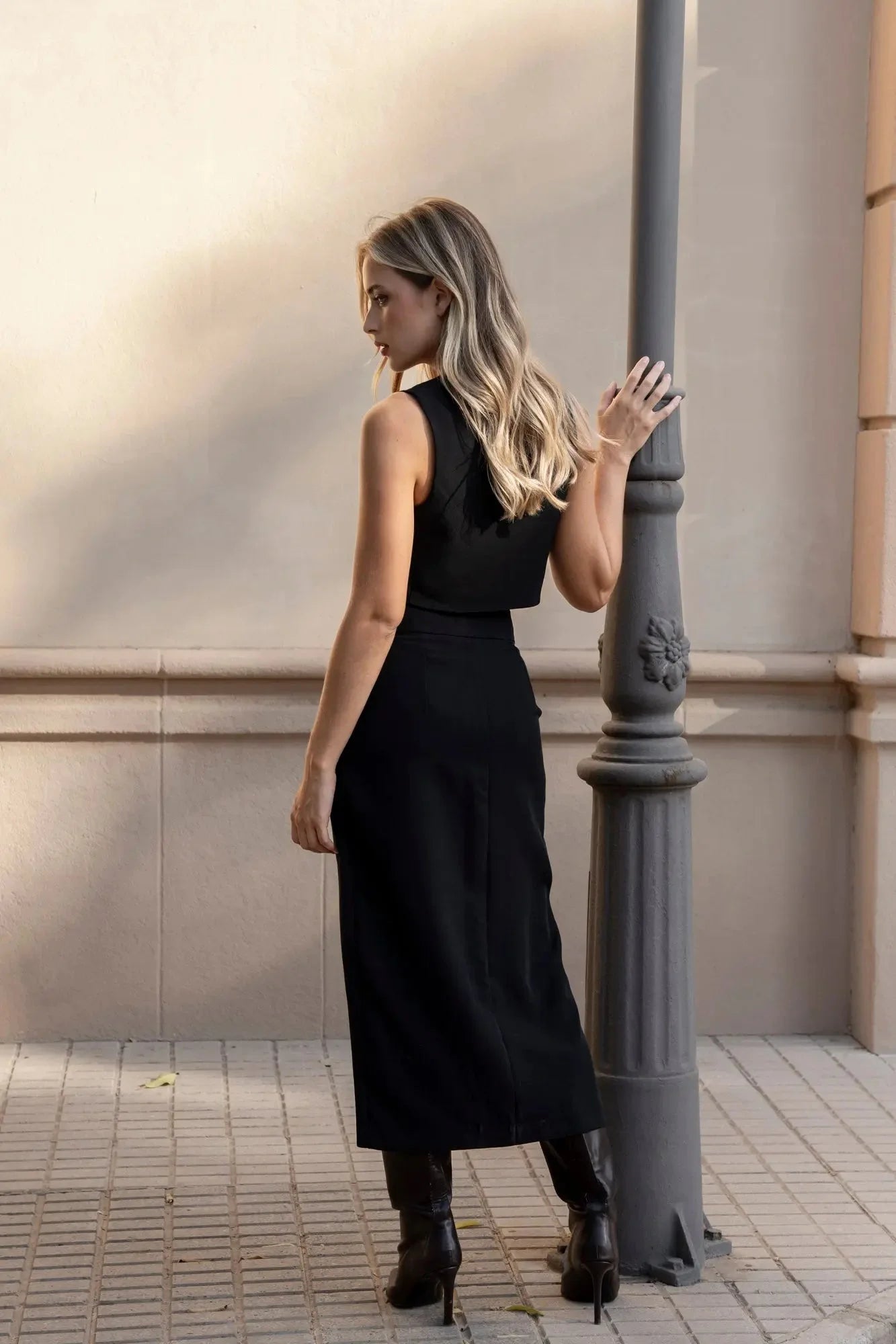 Vue arrière d'une femme dans une jupe noire fendue, ajoutant une touche de sophistication à son look.