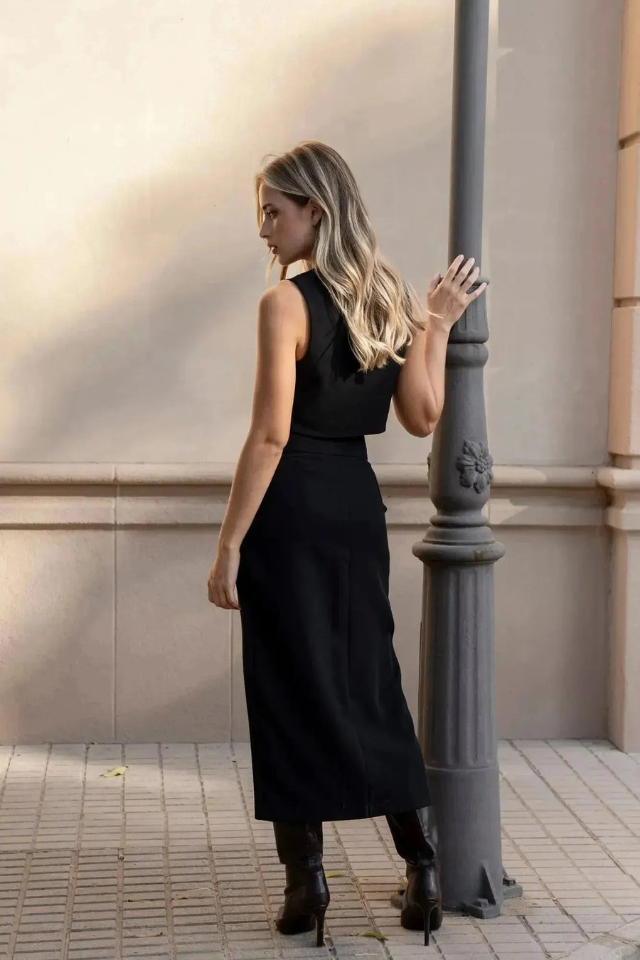 Vue arrière d'une femme dans une jupe noire fendue, ajoutant une touche de sophistication à son look.
