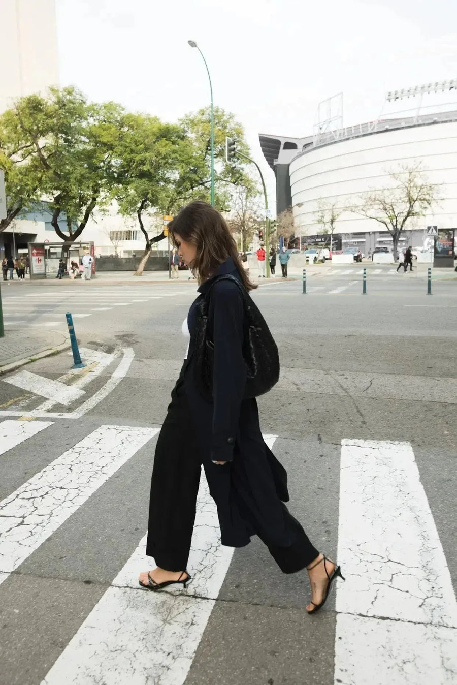 Femme marchant avec élégance, portant un ensemble gilet et pantalon large, mettant en avant le style pantalon à revers femme dans un cadre urbain.