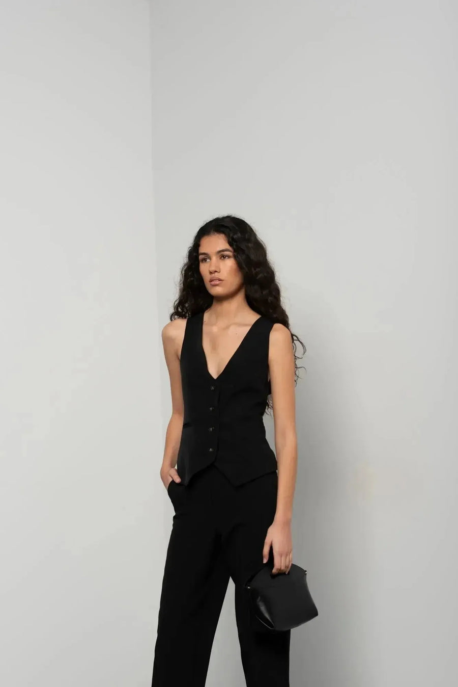 Portrait d'une femme dans un gilet noir et pantalon à revers femme, soulignant un style élégant et contemporain.