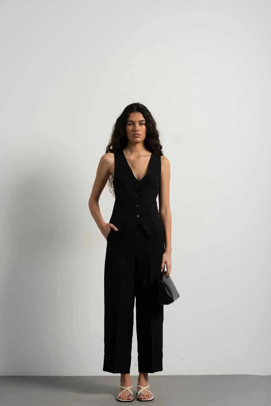 Modèle posant avec assurance dans un ensemble gilet noir et pantalon à revers femme, mettant en valeur l'élégance et le confort.