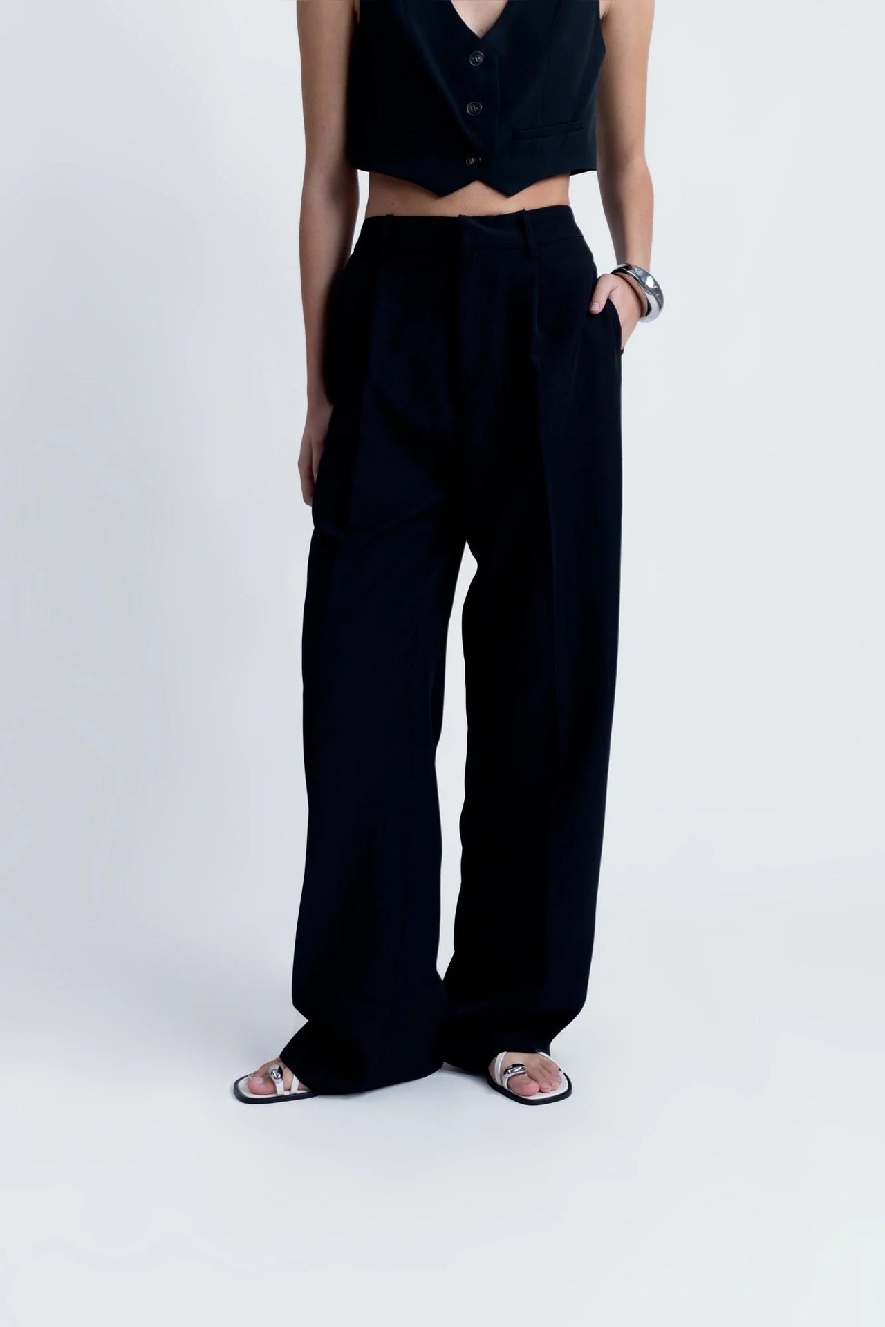 Modèle posant avec assurance dans le Pantalon Noir Fluide Femme Élégant à Pinces en Polyester Recyclé, affichant son style tendance.