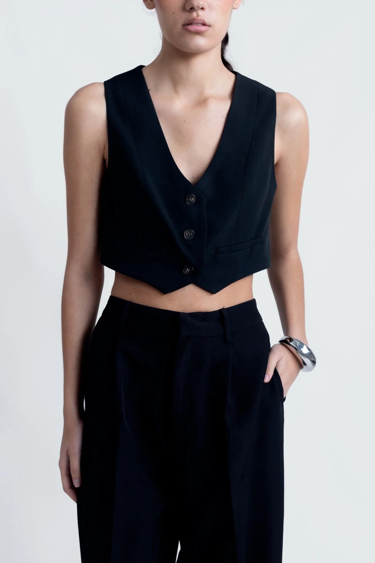 Zoom sur le haut et les détails du Pantalon Noir Fluide Femme Élégant à Pinces en Polyester Recyclé, mettant en avant la silhouette chic.