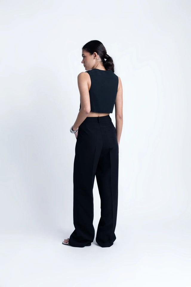 Pantalon Noir Fluide Femme Élégant à Pinces en Polyester Recyclé, vue arrière d'un modèle élégant portant un top court.