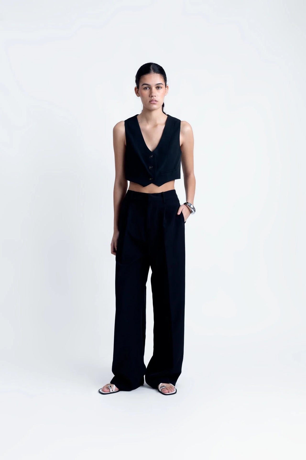 Pantalon Noir Fluide Femme Élégant à Pinces en Polyester Recyclé, modèle présenté debout avec un top court, exhalant style et confort.