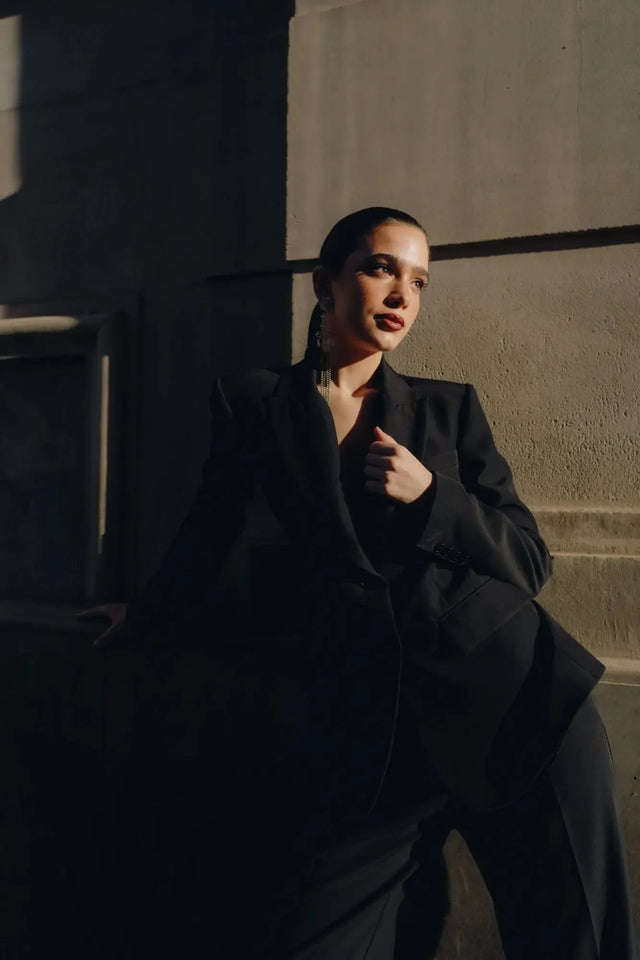 Pantalon Noir Fluide Femme Élégant à Pinces en Polyester Recyclé, modèle dégageant confiance et style dans une pose élégante.